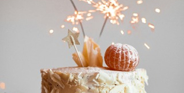 Bolo de aniversário branco e laranja com velas acesas em cima