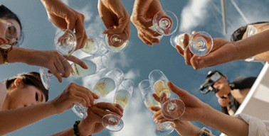 Várias pessoas brindando com taças de champagne a céu aberto