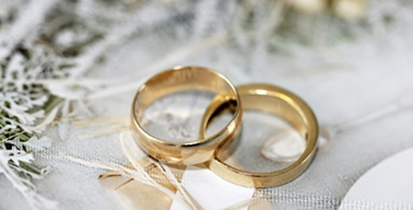 Alianças douradas de casamento uma em cima da outra em uma mesa branca